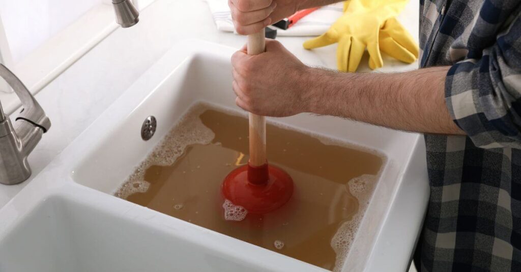 Plunger being used to clear a blocked vanity sink.